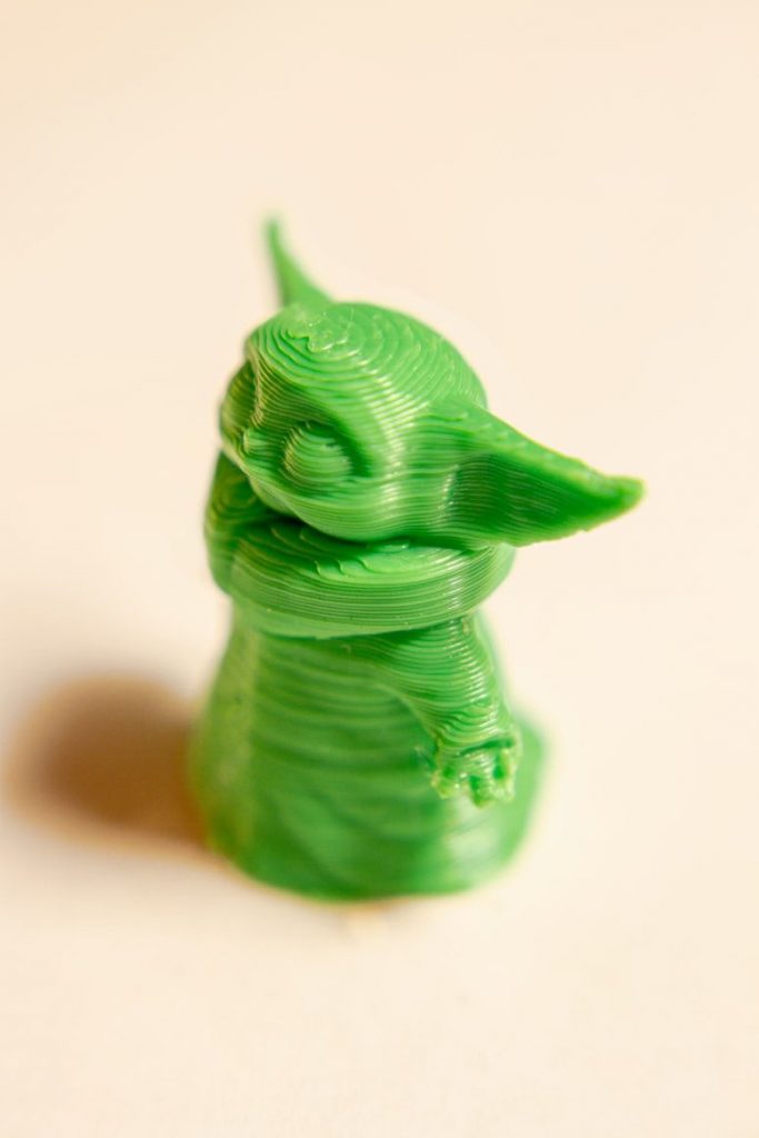 green 3d printed figure of grogu (baby yoda) on neutral background