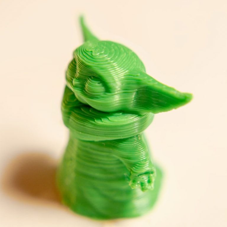 green 3d printed figure of grogu (baby yoda) on neutral background