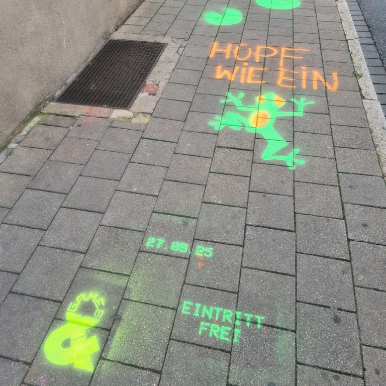 Straßenkreide-Spiele auf in grellen Farben auf dem Gehsteig. Dazu Games&Logo, das Datum 27.09. und Eintritt frei!
